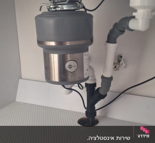 מתקן טוחן אשפה מתחת לכיור עם צינורות חיבור